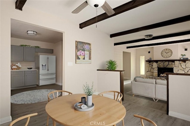 833 E Victoria, Lake Arrowhead, CA 92352 - dining room with a ceiling fan, wood finished floors, beam ceiling, and a stone fireplace