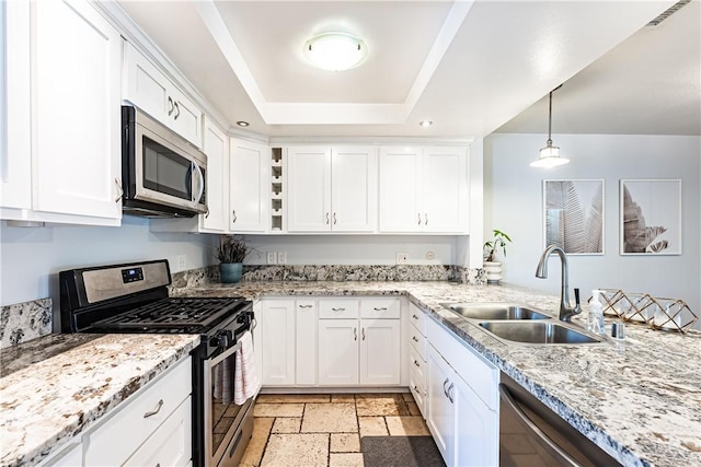 1209 E 1st St, Tustin, CA 92780 - kitchen featuring appliances with stainless steel finishes, a raised ceiling, white cabinets, stone tile flooring, and hanging light fixtures