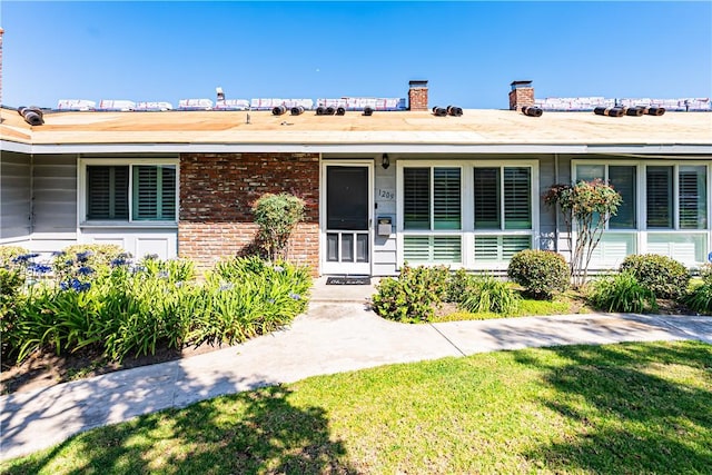 1209 E 1st St, Tustin, CA 92780 - doorway to property with a chimney, brick siding, and a lawn