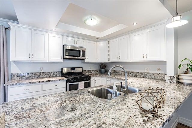 1209 E 1st St, Tustin, CA 92780 - kitchen with appliances with stainless steel finishes, white cabinets, a tray ceiling, light stone countertops, and pendant lighting