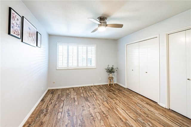 1209 E 1st St, Tustin, CA 92780 - unfurnished bedroom with wood finished floors, two closets, and ceiling fan