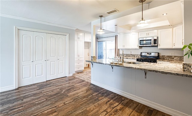 1209 E 1st St, Tustin, CA 92780 - kitchen with appliances with stainless steel finishes, hardwood / wood-style floors, stone counters, a peninsula, and white cabinetry