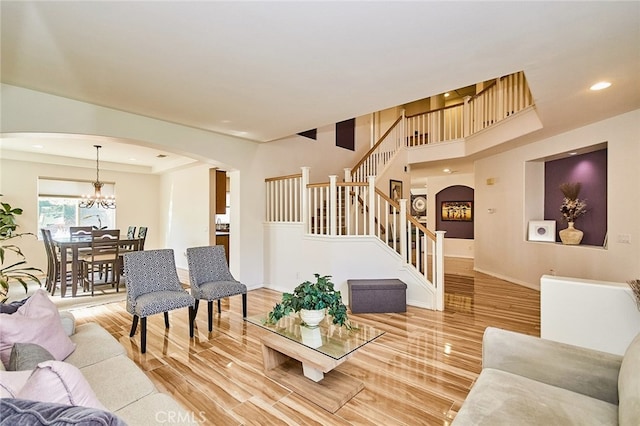 13637 Aspen Leaf Ln, Eastvale, CA 92880 - living room featuring arched walkways, light wood-style flooring, stairway, a chandelier, and recessed lighting