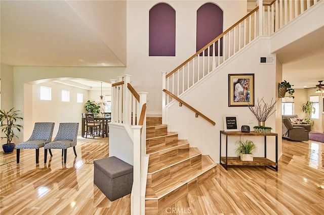13637 Aspen Leaf Ln, Eastvale, CA 92880 - stairs featuring arched walkways, wood finished floors, a high ceiling, and ceiling fan