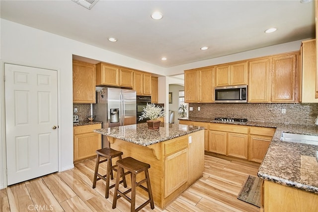 13637 Aspen Leaf Ln, Eastvale, CA 92880 - kitchen with appliances with stainless steel finishes, stone counters, a center island, light wood finished floors, and recessed lighting