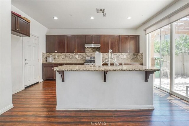 16202 Orion Ave, Chino, CA 91708 - kitchen with under cabinet range hood, tasteful backsplash, dark wood-type flooring, a kitchen island with sink, and recessed lighting