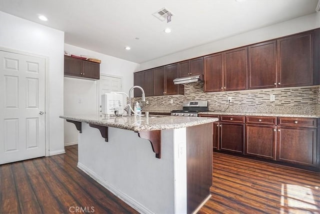 16202 Orion Ave, Chino, CA 91708 - kitchen featuring stainless steel range oven, under cabinet range hood, dark wood-style flooring, tasteful backsplash, and light stone countertops