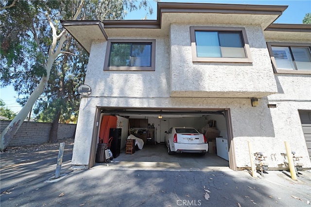 18560 Vanowen St Unit 27, Reseda, CA 91335 - view of front of property featuring stucco siding, a garage, and driveway