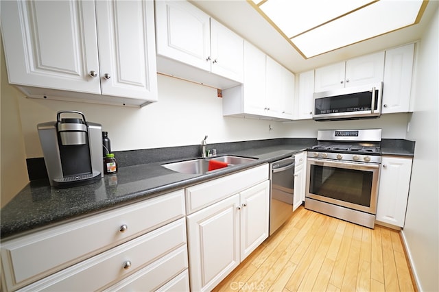 18560 Vanowen St Unit 27, Reseda, CA 91335 - kitchen featuring appliances with stainless steel finishes, light wood-type flooring, dark countertops, and white cabinetry