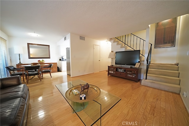 18560 Vanowen St Unit 27, Reseda, CA 91335 - living room featuring stairway, light wood-type flooring, and a textured ceiling