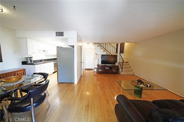 18560 Vanowen St Unit 27, Reseda, CA 91335 - living area featuring light wood-style floors, stairs, and a textured ceiling