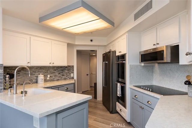 222 Monterey Rd Unit 1205, Glendale, CA 91206 - kitchen with stainless steel appliances, white cabinetry, tasteful backsplash, and light wood finished floors