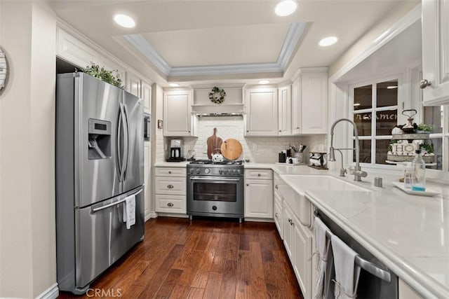 20072 Mural Cir, Huntington Beach, CA 92646 - kitchen featuring appliances with stainless steel finishes, a tray ceiling, white cabinetry, crown molding, and tasteful backsplash