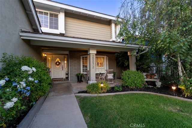 20072 Mural Cir, Huntington Beach, CA 92646 - property entrance with covered porch, a yard, and stucco siding