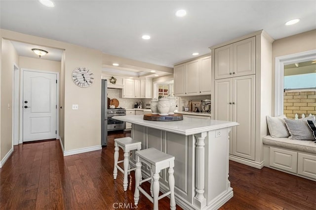 20072 Mural Cir, Huntington Beach, CA 92646 - kitchen featuring a breakfast bar, dark wood finished floors, a kitchen island, light countertops, and appliances with stainless steel finishes