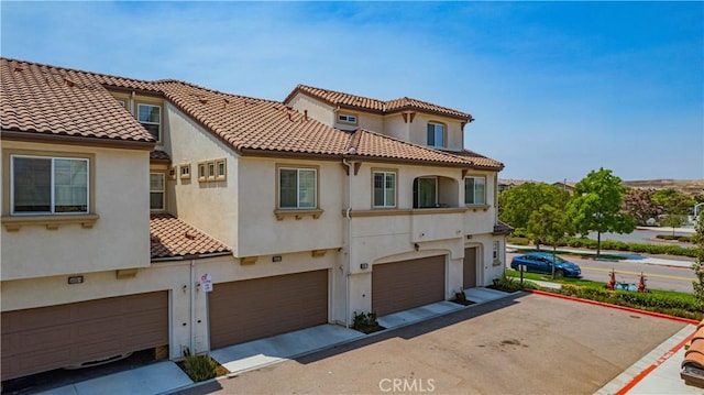 1405 Santa Victoria Rd Unit 2, Chula Vista, CA 91913 - back of house featuring stucco siding, a garage, a tiled roof, and driveway