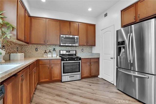 1405 Santa Victoria Rd Unit 2, Chula Vista, CA 91913 - kitchen with appliances with stainless steel finishes, brown cabinetry, decorative backsplash, light wood-style floors, and recessed lighting