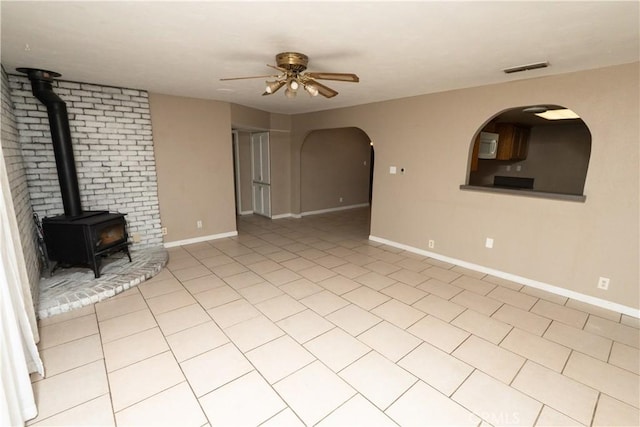 906 E 22nd St, Merced, CA 95340 - unfurnished living room with ceiling fan, a wood stove, light tile patterned floors, and arched walkways