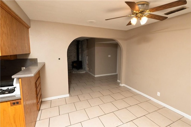 906 E 22nd St, Merced, CA 95340 - empty room with a wood stove, a ceiling fan, arched walkways, and light tile patterned floors