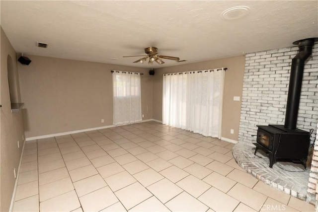 906 E 22nd St, Merced, CA 95340 - unfurnished living room featuring a wood stove, ceiling fan, and light tile patterned floors