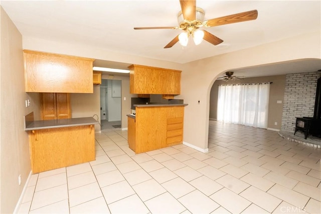 906 E 22nd St, Merced, CA 95340 - kitchen with open floor plan, a wood stove, arched walkways, a ceiling fan, and a peninsula