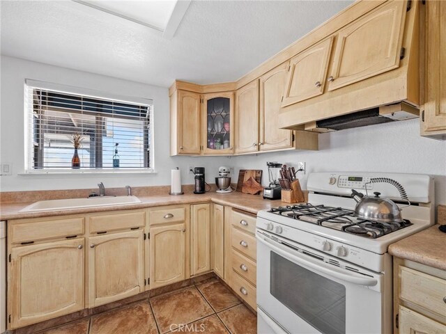 1233 Cabrillo Dr, Barstow, CA 92311 - kitchen with white range with gas stovetop, light brown cabinets, a textured ceiling, light countertops, and light tile patterned flooring