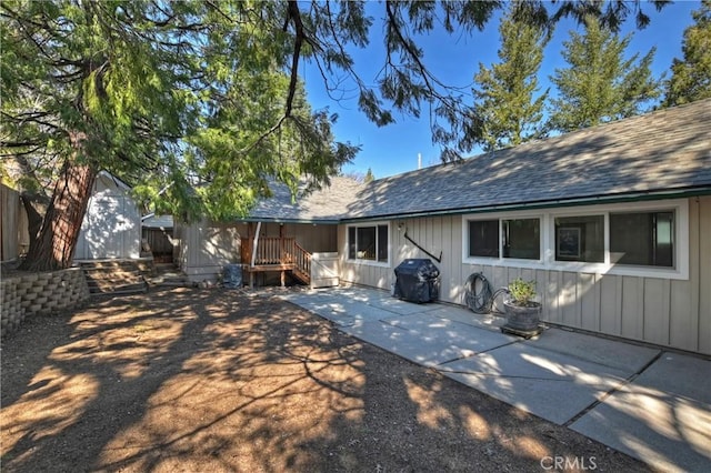 292 Heliotrope Dr, Lake Arrowhead, CA 92352 - rear view of house featuring a patio, a shed, a shingled roof, and board and batten siding