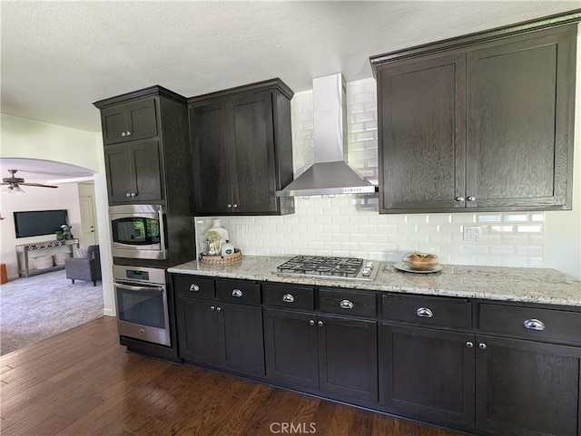 1785 Durham Dayton, Durham, CA 95938 - kitchen featuring appliances with stainless steel finishes, wall chimney range hood, dark wood-type flooring, a ceiling fan, and decorative backsplash