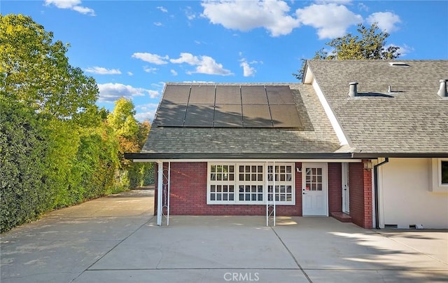 1785 Durham Dayton, Durham, CA 95938 - rear view of property featuring a shingled roof, solar panels, brick siding, and a patio area