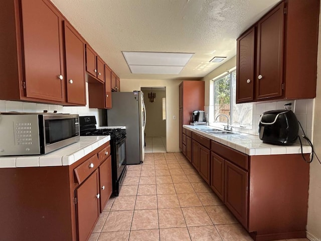 3010 Parkside Pl, San Diego, CA 92139 - kitchen with stainless steel appliances, tile counters, tasteful backsplash, light tile patterned floors, and a textured ceiling