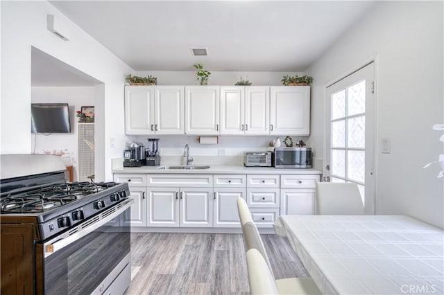 4430 W 166th St, Lawndale, CA 90260 - kitchen with appliances with stainless steel finishes, white cabinetry, light wood finished floors, and tile countertops