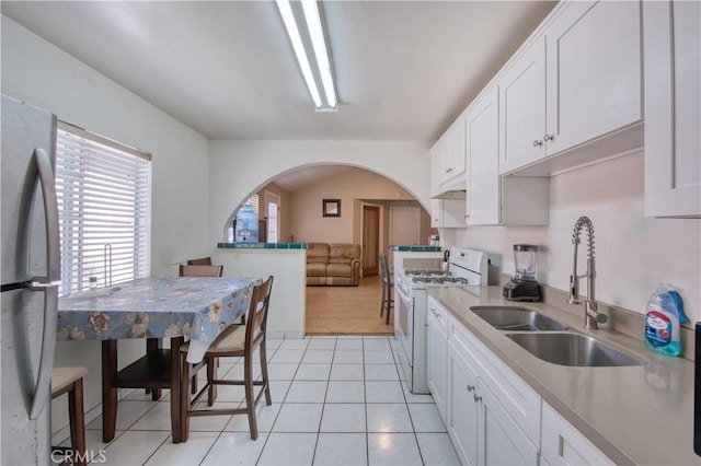 4430 W 166th St, Lawndale, CA 90260 - kitchen featuring white gas range, freestanding refrigerator, arched walkways, white cabinetry, and light tile patterned floors