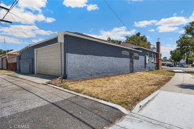 313 S Pickering Way, Montebello, CA 90640 - view of side of property with stucco siding, asphalt driveway, and a garage
