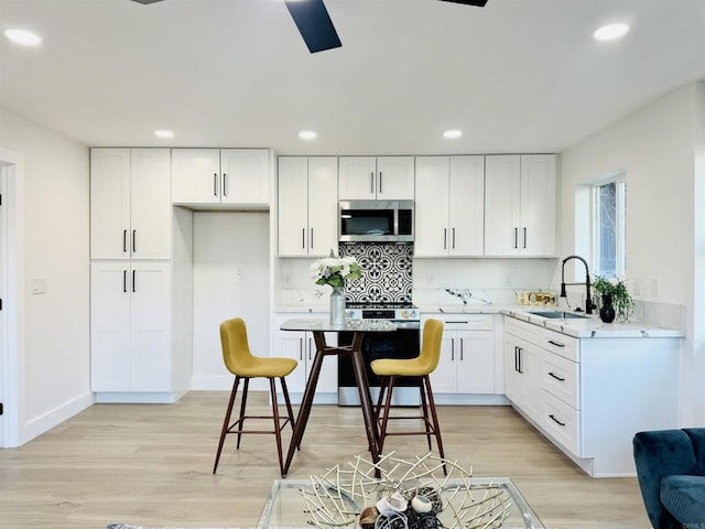 7118 Stanford Ave, La Mesa, CA 91942 - kitchen with appliances with stainless steel finishes, recessed lighting, light wood finished floors, and white cabinets