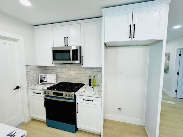 7118 Stanford Ave, La Mesa, CA 91942 - kitchen featuring appliances with stainless steel finishes, light wood-style flooring, backsplash, white cabinetry, and light stone counters