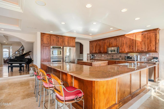 2110 Ravoli Dr, Oxnard, CA 93035 - kitchen featuring arched walkways, stainless steel appliances, a large island, a raised ceiling, and tasteful backsplash