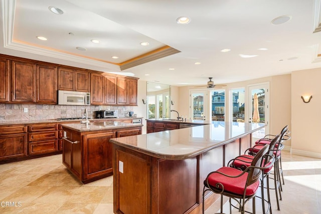 2110 Ravoli Dr, Oxnard, CA 93035 - kitchen featuring a large island with sink, backsplash, a tray ceiling, ornamental molding, and recessed lighting
