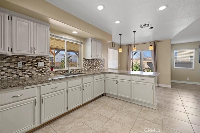 43939 Glenraven Rd, Lancaster, CA 93535 - kitchen featuring backsplash, a peninsula, recessed lighting, stone countertops, and light tile patterned flooring