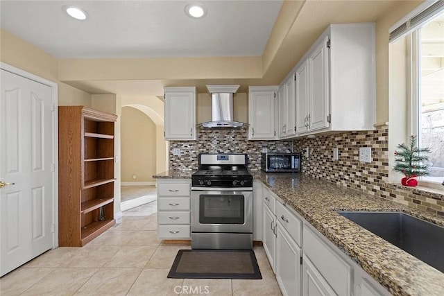 43939 Glenraven Rd, Lancaster, CA 93535 - kitchen featuring stainless steel gas stove, wall chimney range hood, backsplash, stone counters, and light tile patterned floors