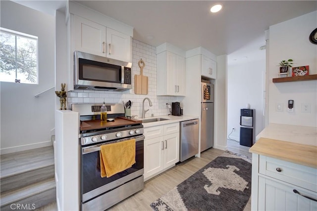 5926 Gran Paseo Way, Atascadero, CA 93422 - kitchen with appliances with stainless steel finishes, white cabinetry, backsplash, light wood-style flooring, and open shelves