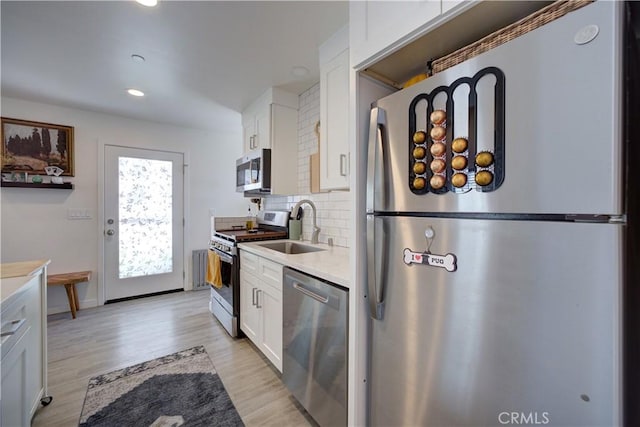 5926 Gran Paseo Way, Atascadero, CA 93422 - kitchen featuring stainless steel appliances, white cabinets, decorative backsplash, light wood finished floors, and light countertops