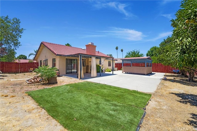41384 Collegian Way, Hemet, CA 92544 - back of house featuring a patio area, a chimney, a hot tub, and a fenced backyard