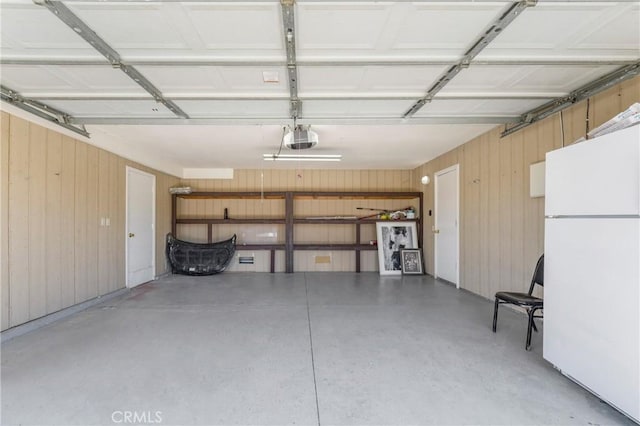 41384 Collegian Way, Hemet, CA 92544 - garage featuring freestanding refrigerator, a garage door opener, and wooden walls