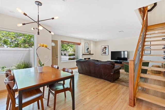 2005 Countrywood Ct, Encinitas, CA 92024 - dining space with stairway, light wood-type flooring, a chandelier, and a lit fireplace