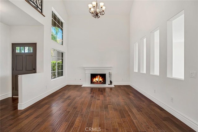 19900 Mariposa Creek Way, Porter Ranch, CA 91326 - unfurnished living room with a chandelier, a high ceiling, dark wood-type flooring, and a warm lit fireplace