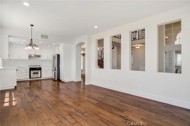 19900 Mariposa Creek Way, Porter Ranch, CA 91326 - unfurnished living room featuring dark wood finished floors, recessed lighting, a chandelier, and arched walkways