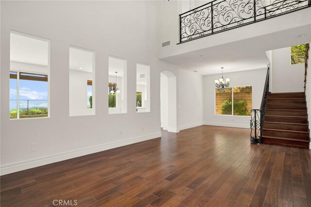19900 Mariposa Creek Way, Porter Ranch, CA 91326 - unfurnished living room featuring a chandelier, dark wood finished floors, arched walkways, stairs, and a high ceiling