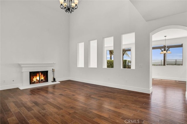 19900 Mariposa Creek Way, Porter Ranch, CA 91326 - unfurnished living room featuring a chandelier, dark wood-type flooring, a lit fireplace, and arched walkways