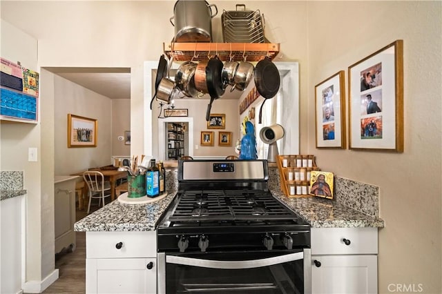 1711 Shasta St, Anderson, CA 96007 - kitchen with stainless steel gas stove, white cabinets, light stone countertops, and wood finished floors