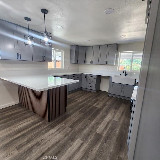 3087 N Lugo Ave, San Bernardino, CA 92404 - kitchen featuring gray cabinetry, dark wood-type flooring, a textured ceiling, light countertops, and a peninsula